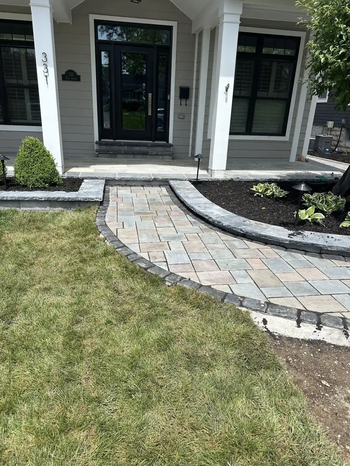 Curved paver walkway with landscaped mulch beds by Green Operations