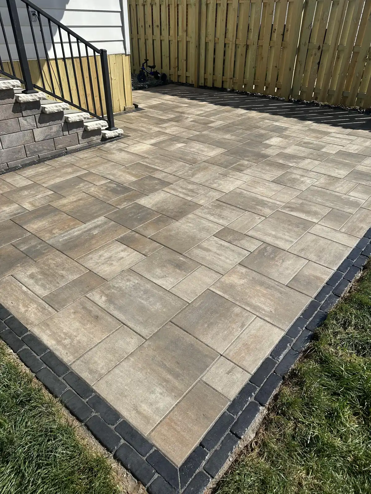 Large-format herringbone paver patio with privacy fence in St. Louis