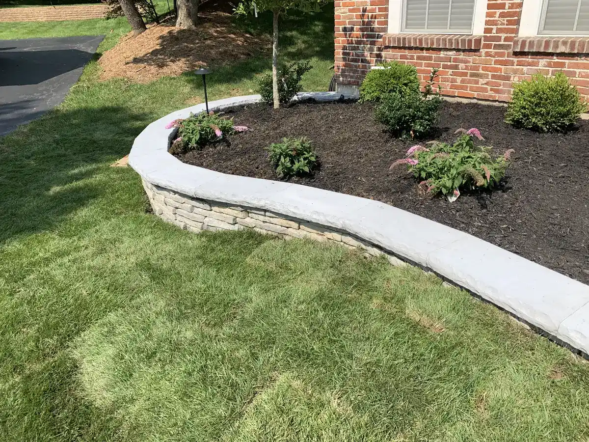 Curved stone planter wall with colorful flowers and shrubs