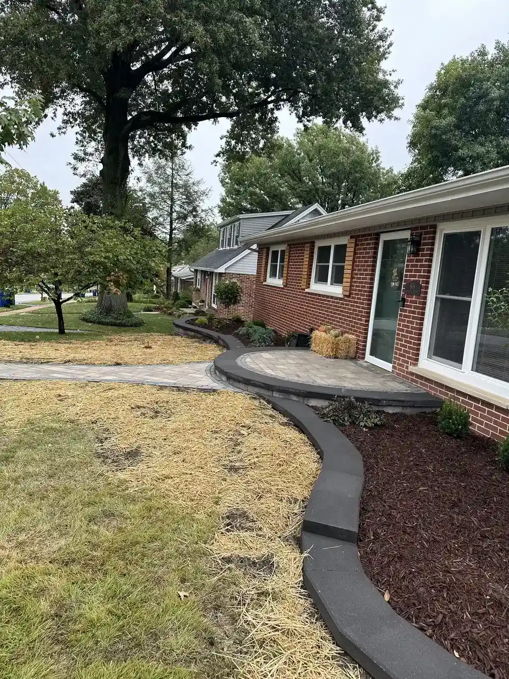 Well-maintained lawn with crisp mulch bed edging along a brick house in St. Louis