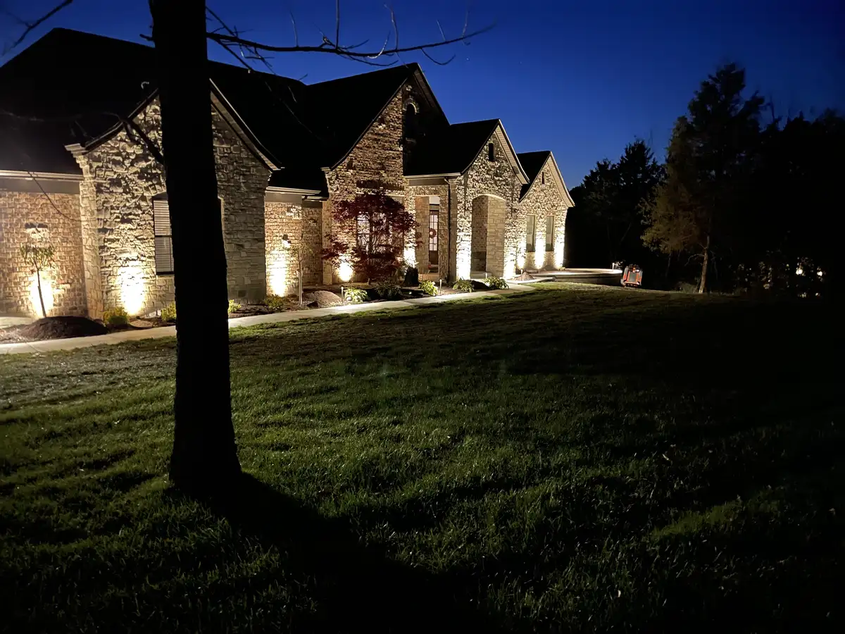 Stone mansion with professional landscape uplighting at night in St. Louis