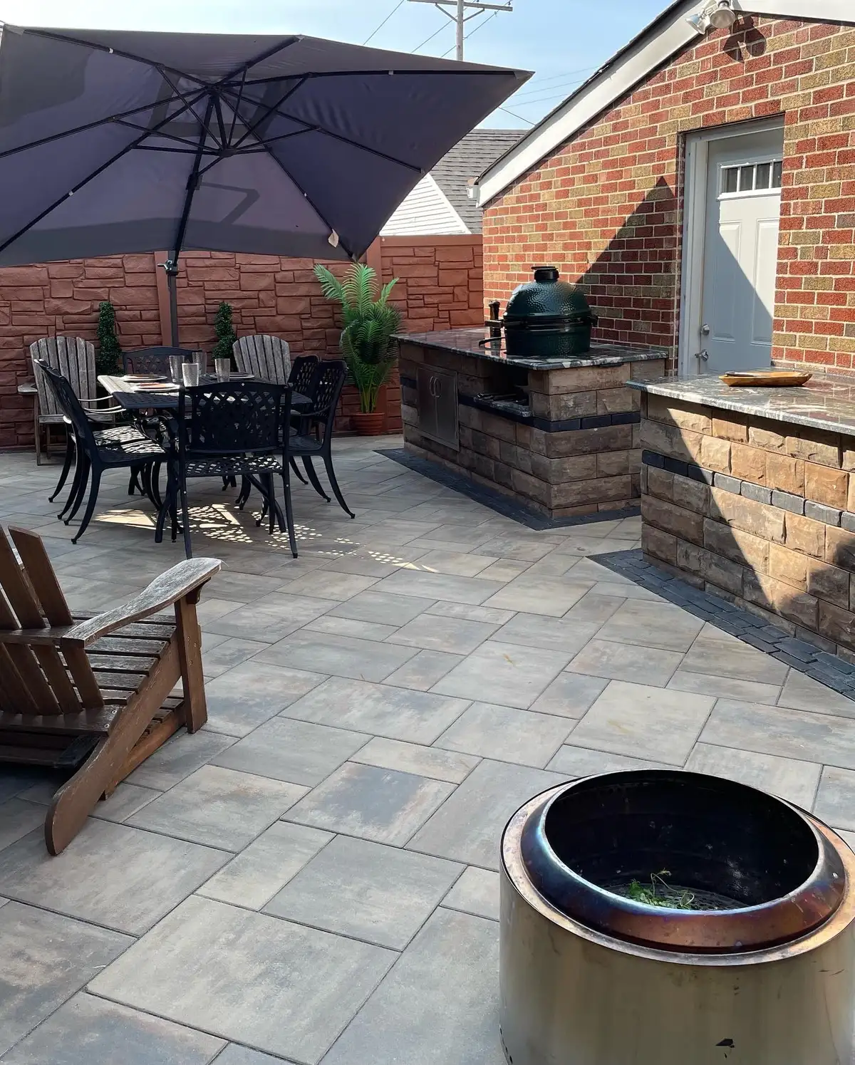 Complete outdoor living space with kitchen, fire pit, and dining area built by Green Operations