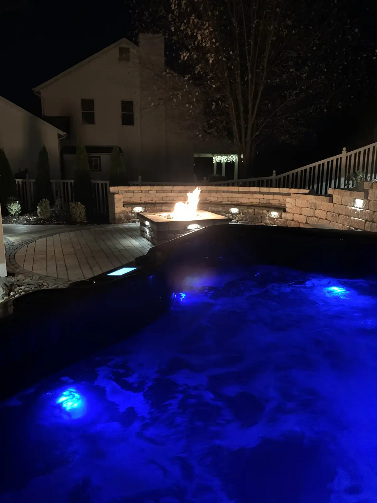 Night view of pool with LED lighting, fire feature, and pergola in St. Louis
