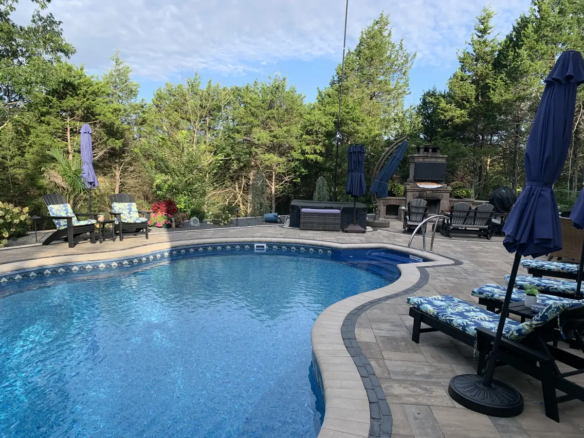 Pool with paver deck and outdoor living area including TV and fireplace