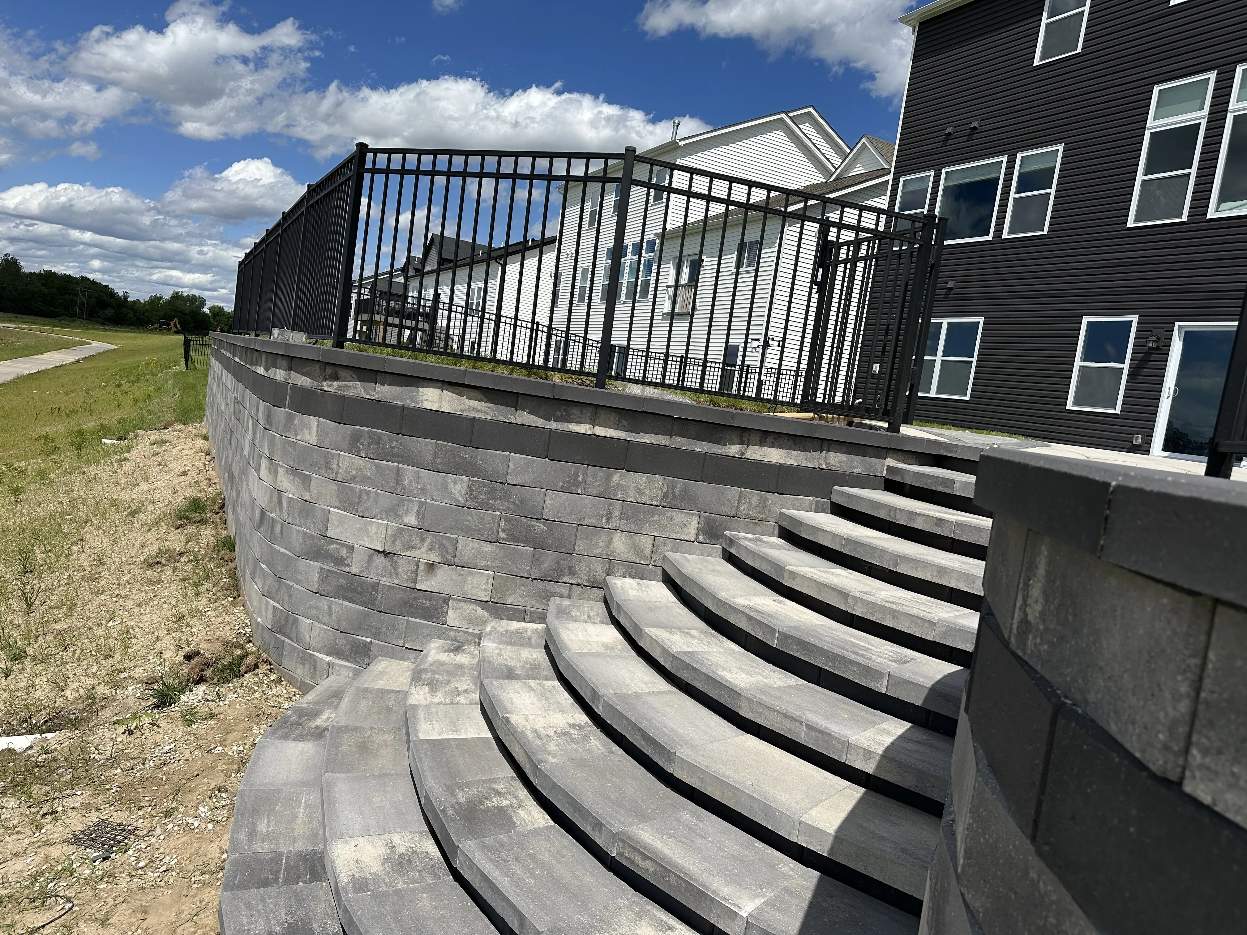 Tall retaining wall with curved steps managing dramatic grade change