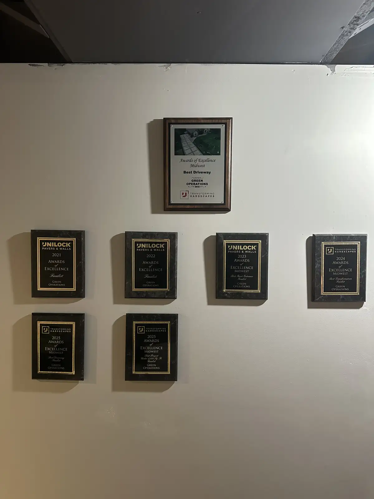 Green Operations Unilock awards and contractor recognition displayed on the shop wall